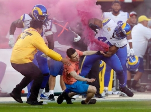 Bobby Wagner, de los Rams de Los &Aacute;ngeles, taclea a un activista que entr&oacute; al campo de juego